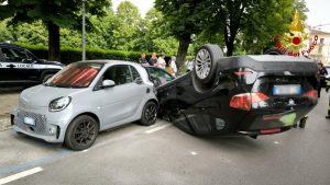 Si schianta contro due vetture parcheggiate, l'auto finisce capovolta 